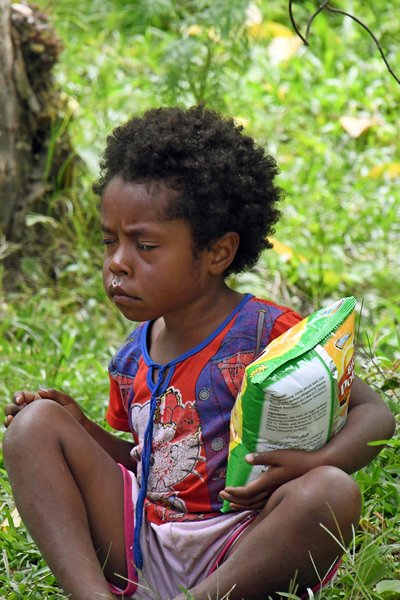 Meisje met zak chips in Sioubri, Papoea