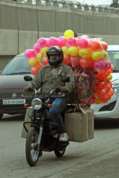 Man op brommer met gekleurde bagage in Delhi (India)