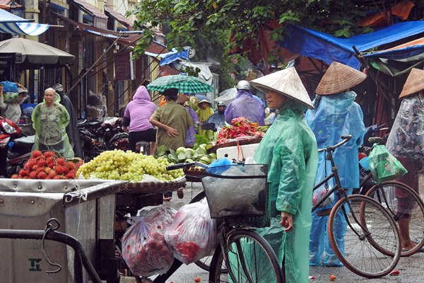 Plastic ponchos en traditionele hoeden op de markt van Hanoi