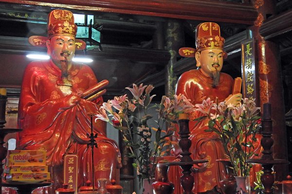 Beelden in de Tempel van de Literatuur met hun offers van kaaswafeltjes in Hanoi