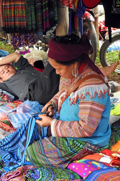 De man rust en de vrouw werkt op de markt van Coc Ly, Vietnam