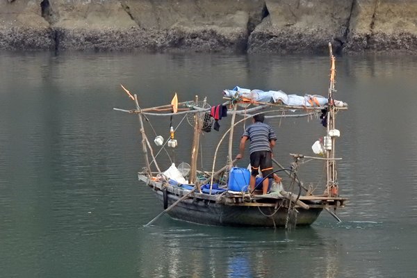 Een visser roeit naar huis in in Halong Bay, Vietnam