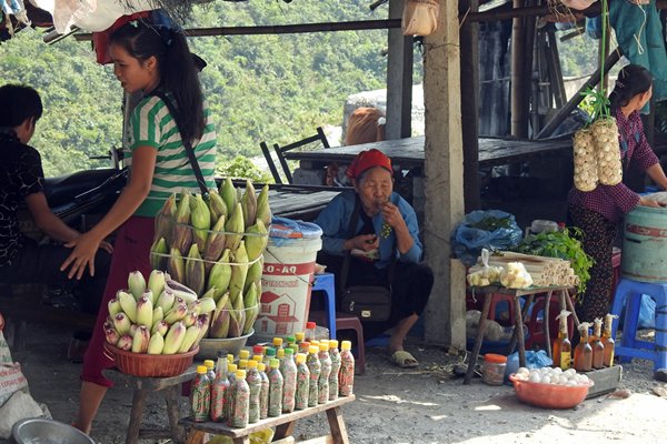 Kraampje met flessen met inhoud, sticky rice, maïs en meer op een lokale markt, Vietnam