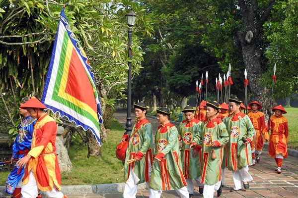 Kleurige wachters met vlaggen paraderen over het terrein van de citadel van Hué, Vietnam