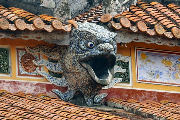 Woest kijkend fantasiedier als gaper tussen de dakpannen in de citadel van Hué, Vietnam