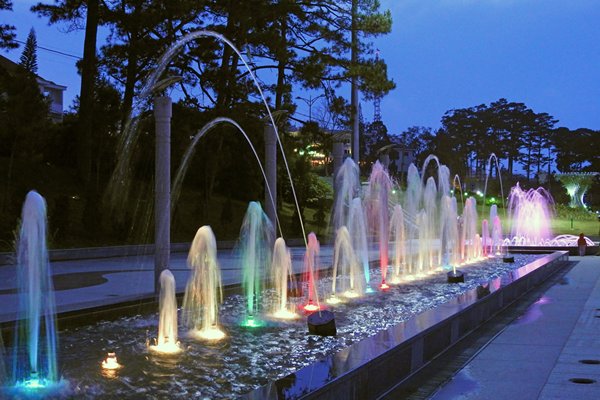 De van kleur en hoogte wisselende reeks fonteinen die het donkere Dalat (Vietnam) versieren