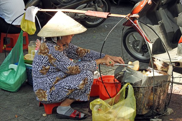 Straatverkoopster met eetstalletje in Saigon