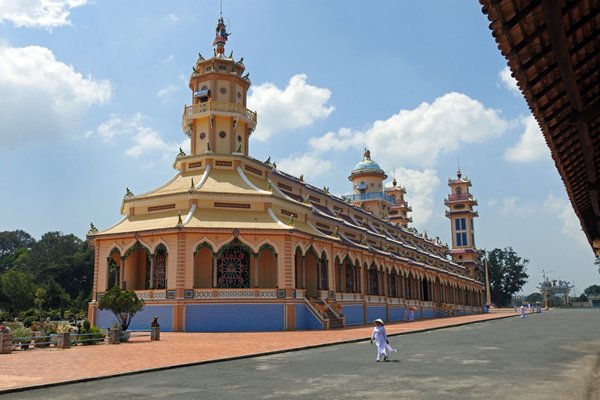 De pastelkleurige Cao Dai tempel met zijn torentjes en versiersels