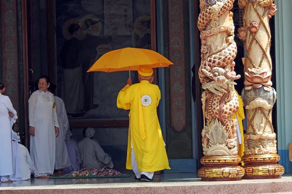 Priester in het geel betreedt de Cao Dai tempel
