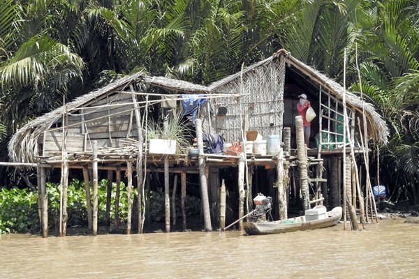 Een huisje langs het water in de Mekong delta. De palen zijn nodig voor de wisselende waterstanden.