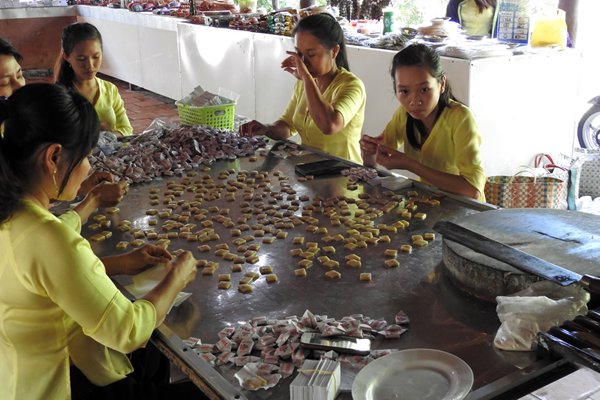 Een groep meisjes in de Mekong delta is bezig met het inpakken van kokossnoepjes
