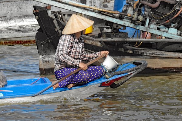 Vrouw op de smalle voorkant van een kleine boot bij Can Tho, Vietnam