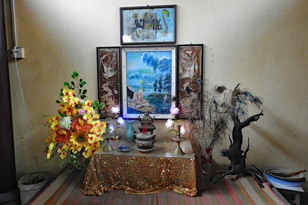 Tafeltje met bloemen, drieluik en pauwenveren in de Binh Thuy tempel bij Can Tho, Vietnam