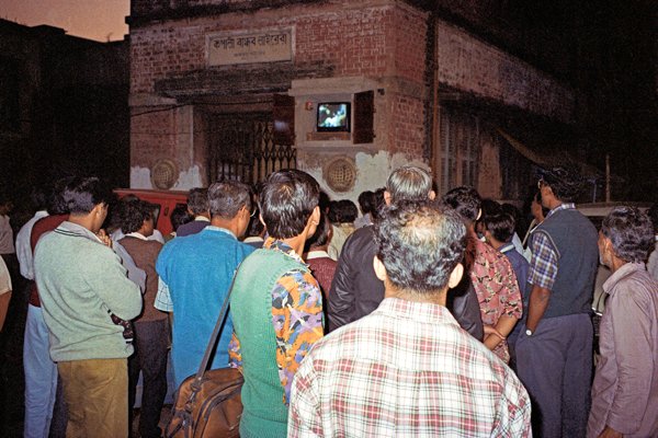 In Calcutta is een TV een paar meter boven de straat in een houen kistje opgesteld