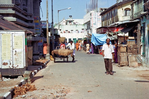 Een rustig straatje in Madras met handkar, troep en een onafgebouwd gebouw