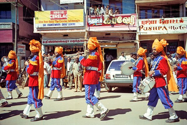 Een muziekkorps met kleurige uniformen bij een processie in Ooty